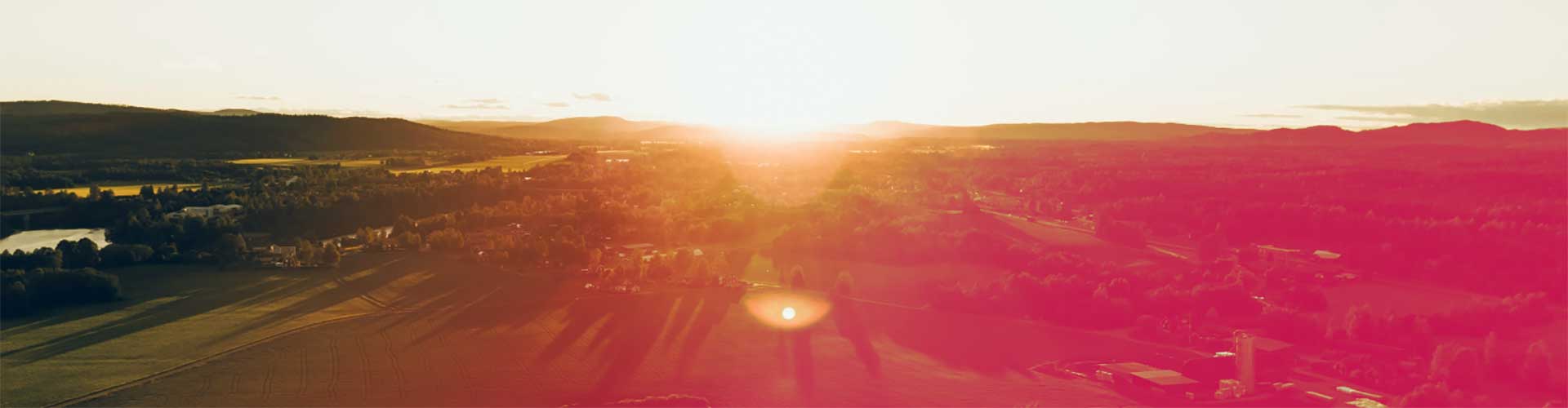 Dorf von oben inmitten von grünen Wiesen und Wäldern beim Sonnenuntergang